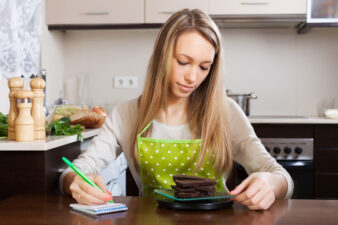 Woman in apron weighing chocolate in kitchen