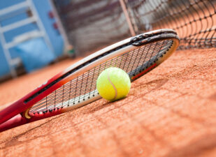 Close up view of tennis racket and ball on the clay tennis court