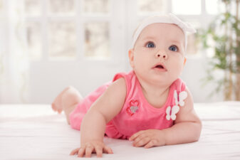 Cute baby girl lying on bed