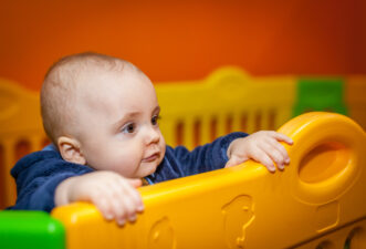 Baby boy standing in a colorful gate