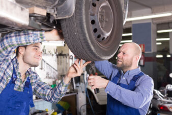 Two men fixing the tire on a car