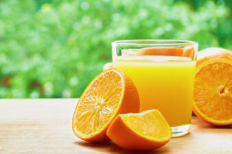 Orange juice and oranges on table