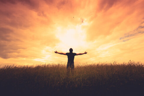 silhouette of man with arms spread to the sunrise