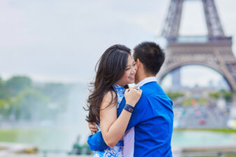 Asian couple hugging outside the Eiffel Tower