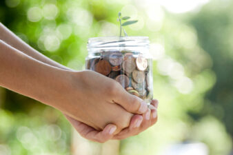 hand holding a jar full of growing coins