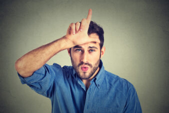 young man doing loser sign on his forehead