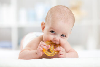 Baby chewing on pretzel shaped teething ring