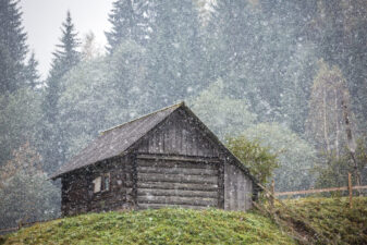 Old country house during heavy snowfall in Carpathians mountains