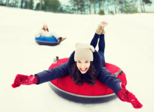 group of happy friends sliding down on snow tubes