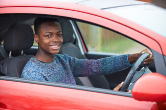 Teenage boy driving red car