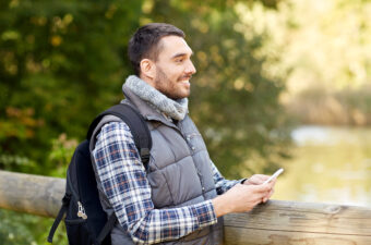 happy man with backpack and smartphone outdoors