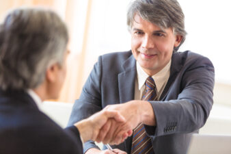 Older man shaking hands with someone across table