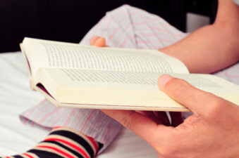 young man reading a book in bed