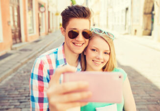 smiling couple with smartphone in city