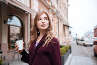 Pensive woman drinking coffee on the street