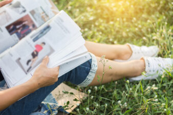 Woman reading a magazine sitting in grass