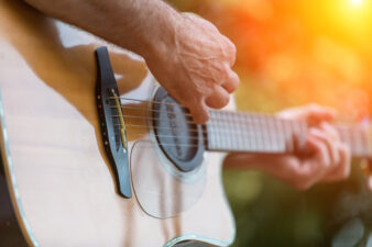 Male hand playing on acoustic guitar