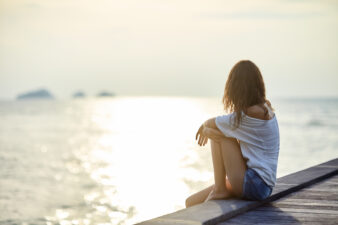 Young woman looking out at the sunset over water