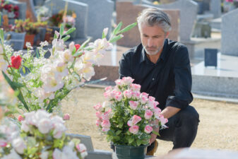 Man in black knelt at grave