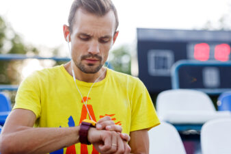 Athletic man looking at watch while listening music in stadium