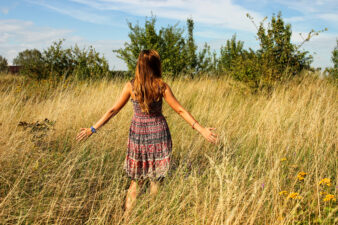 young woman running her hands through a field