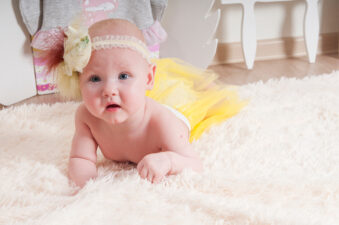 Baby girl playing on the carpet at home or kindergarten