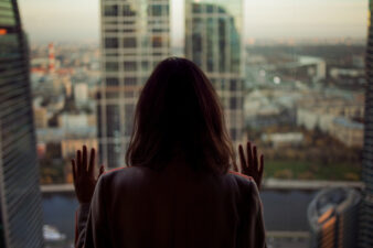 back view of a woman looking longingly out the window