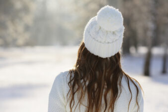 Woman in white hat standing back in a winter park