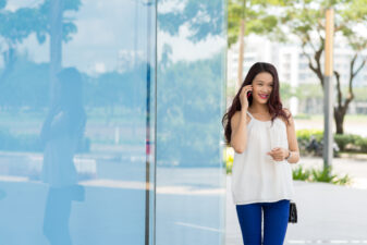 Asian woman walking and talking on phone