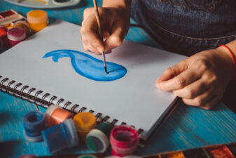 Person drawing a blue whale on a sketchpad