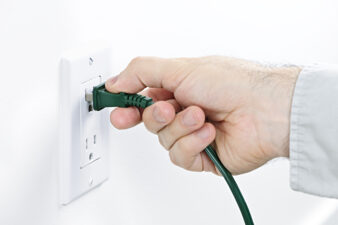 Hand inserting plug into white outlet