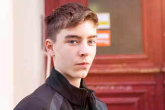 smirking young man in front of red door