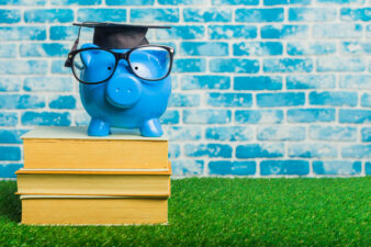 Blue piggy bank with a graduation cap on a stack of books