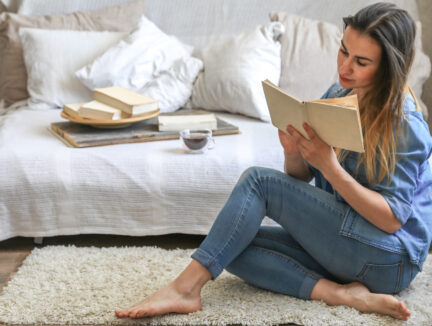 woman sitting on the floor by the couch reading a book