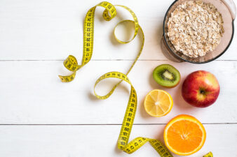 Fitness concept with fruit, bowl of oatmeal and centimeter. Top view background concept.