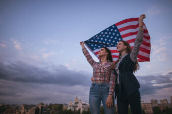 teen girls holding an American flag over their heads