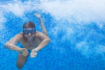 Man swimming underwater in pool