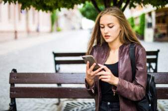 Young woman using her smartphone on a park bench