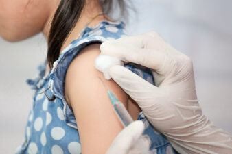 Doctor injecting vaccination in arm of little girl