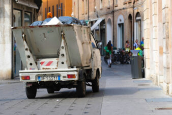 Garbage truck driving through a narrow street