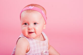 Portrait of the small beautiful joyful girl on a pink background