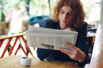 Curly haired man reading the newspaper