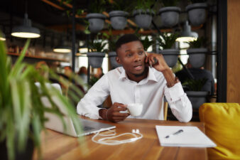 Black businessman talking on the phone at a cafe