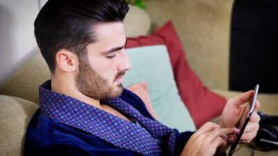 Young man on couch reading with tablet PC