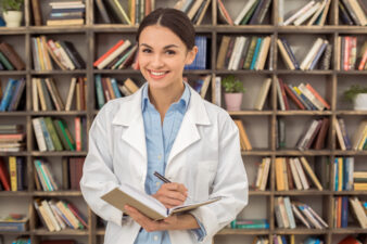 Woman in medical coat writing in a notebook