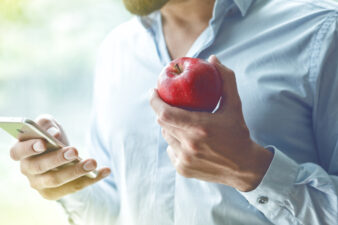 man eating apple looking at phone