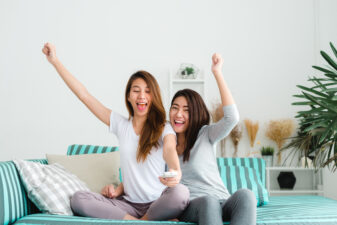 Two women cheering at home