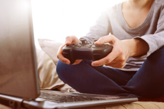 person holding a game controller looking at a laptop