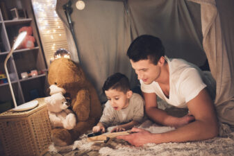 Father and son reading inside of a fort