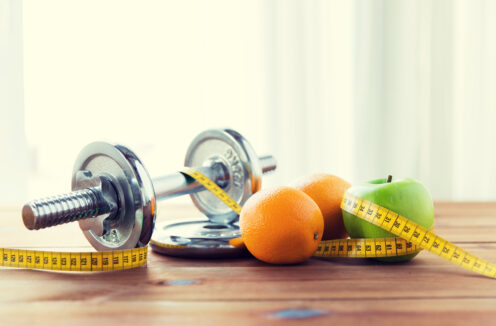 close up of dumbbell, fruits and measuring tape